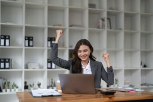 Happy woman office worker feeling excitement raising fists celebrates career ladder promotion or